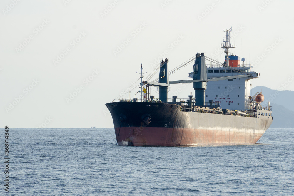 Old commercial cargo ship with heavy cranes anchors in the sea. Old commercial cargo ship with heavy cranes anchors in the sea.