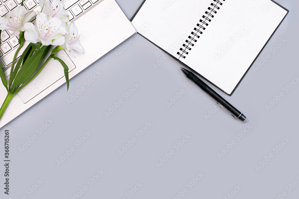 workplace with a laptop Notepad and flowers on a gray background workplace with a laptop Notepad and flowers on a gray background