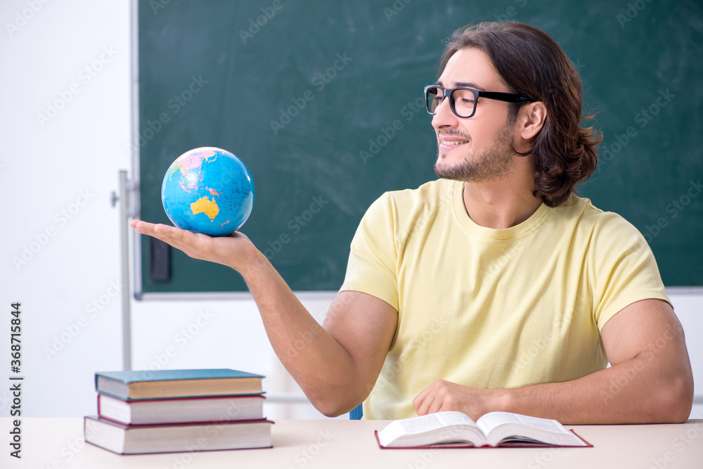 Young male geography teacher in front of blackboard Young male geography teacher in front of blackboard