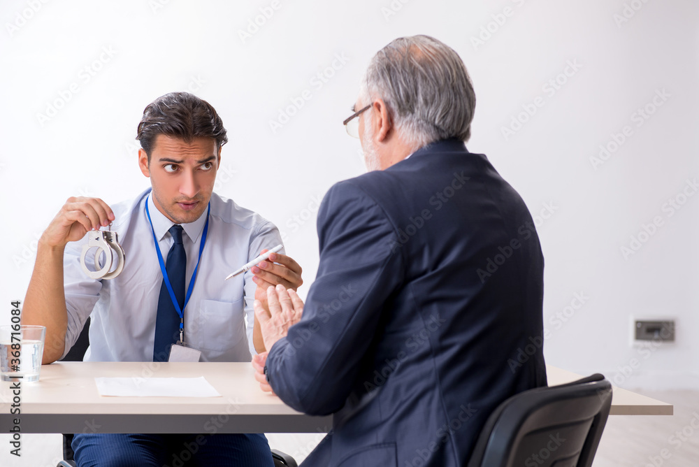 Old businessman meeting with advocate in pre-trial detention Old businessman meeting with advocate in pre-trial detention