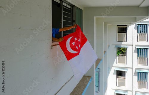 Photography Person hanging Singapore flag outside apartment windows, to welcome national day
