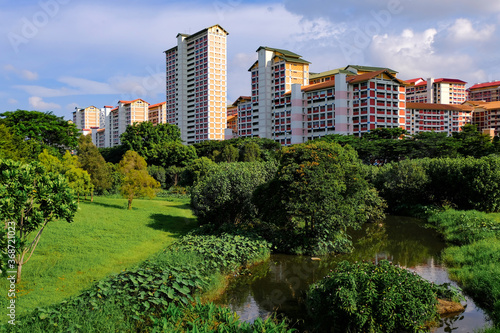 Picturesque view of local colourful public housing in setting of lush greenery, on bright sunny day; blue sky with clouds, Singapore