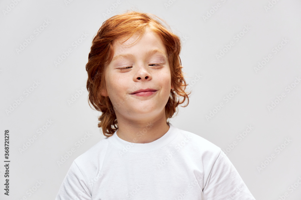 A cheerful boy looks at us on a white T-shirt grimace A cheerful boy looks at us on a white T-shirt grimace