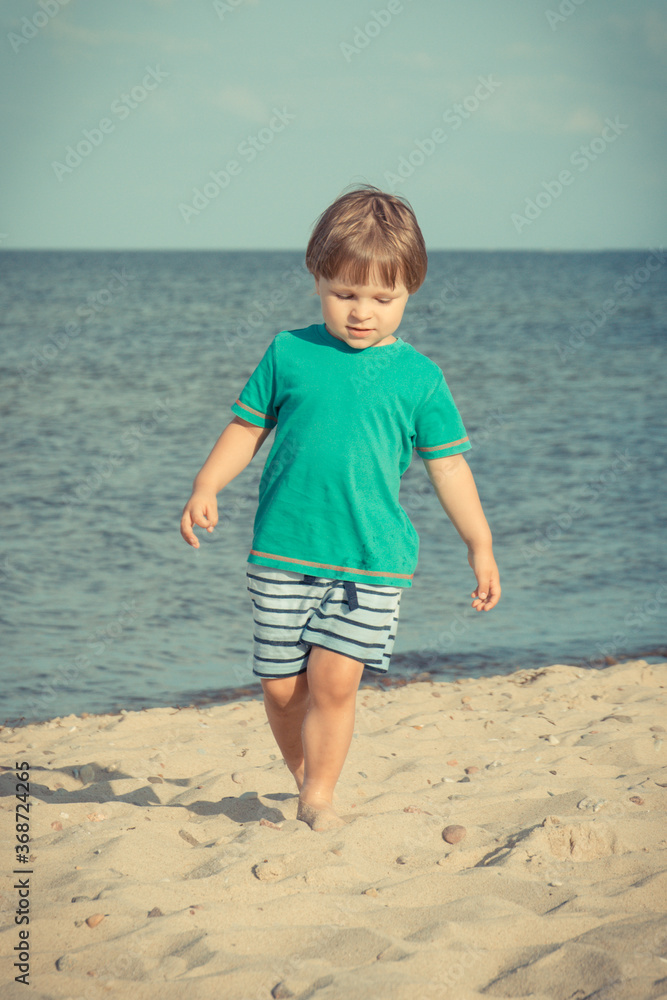 Baby boy walking and playing at summer beach. Vacation time and child development concept Baby boy walking and playing at summer beach. Vacation time and child development concept