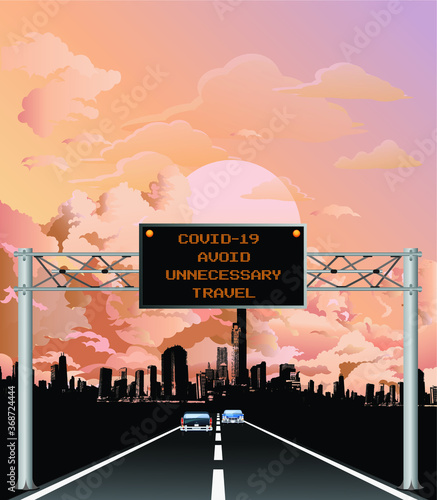 Roadway overhead digital gantry sign with COVID 19 Coronavirus avoid unnecessary travel message set against a dawn or dusk sky 