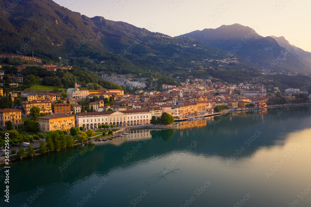 Drone view of Lake Iseo at sunrise, on the left the city of lovere which runs along the lake,Bergamo Italy.