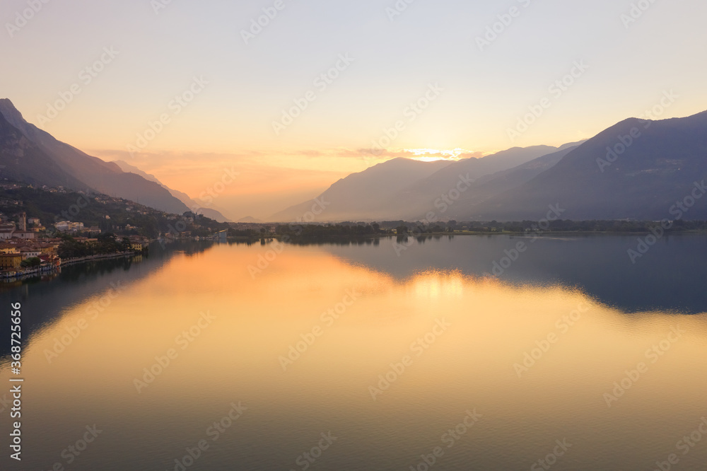Drone view of Lake Iseo at sunrise, on the left the city of lovere which runs along the lake,Bergamo Italy.