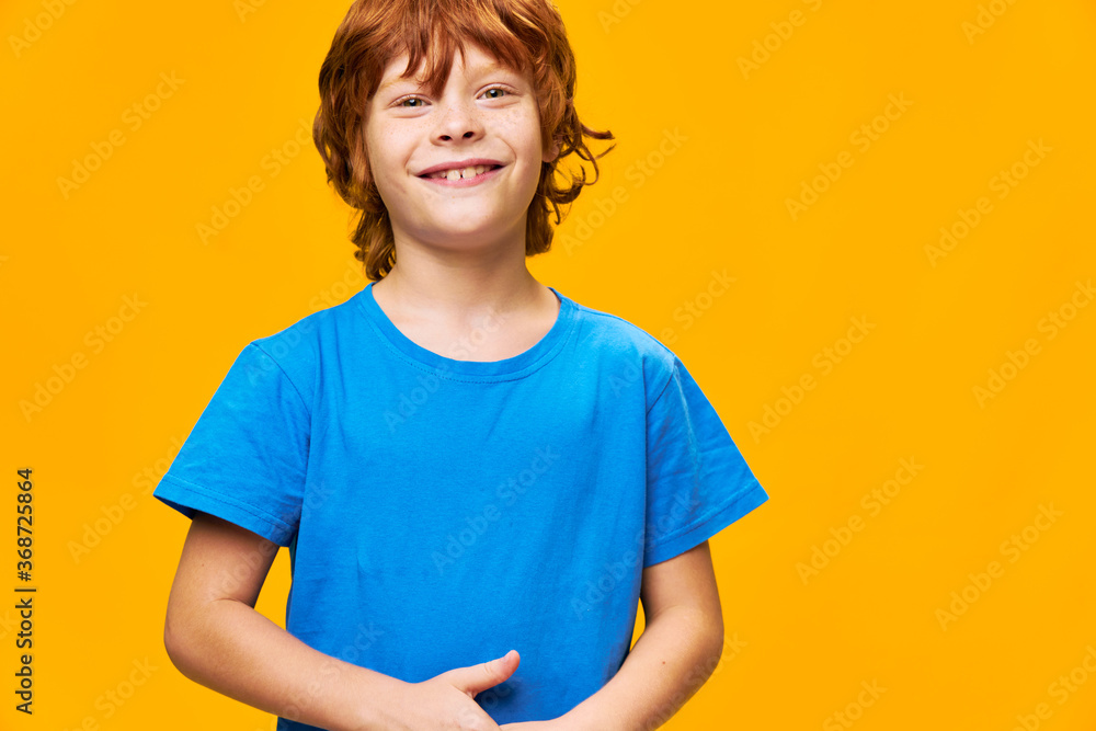red-haired happy boy on yellow background in blue t-shirt red-haired happy boy on yellow background in blue t-shirt