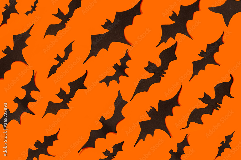 decoration concept for Halloween. Black paper bats fly in one directions on an orange background. template decoration concept for Halloween. Black paper bats fly in one directions on an orange background. template