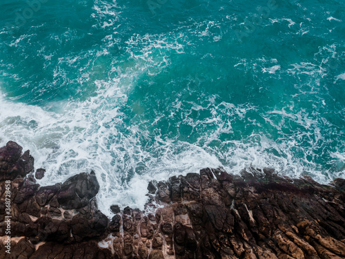 Aerial view of crashing waves on rocks.