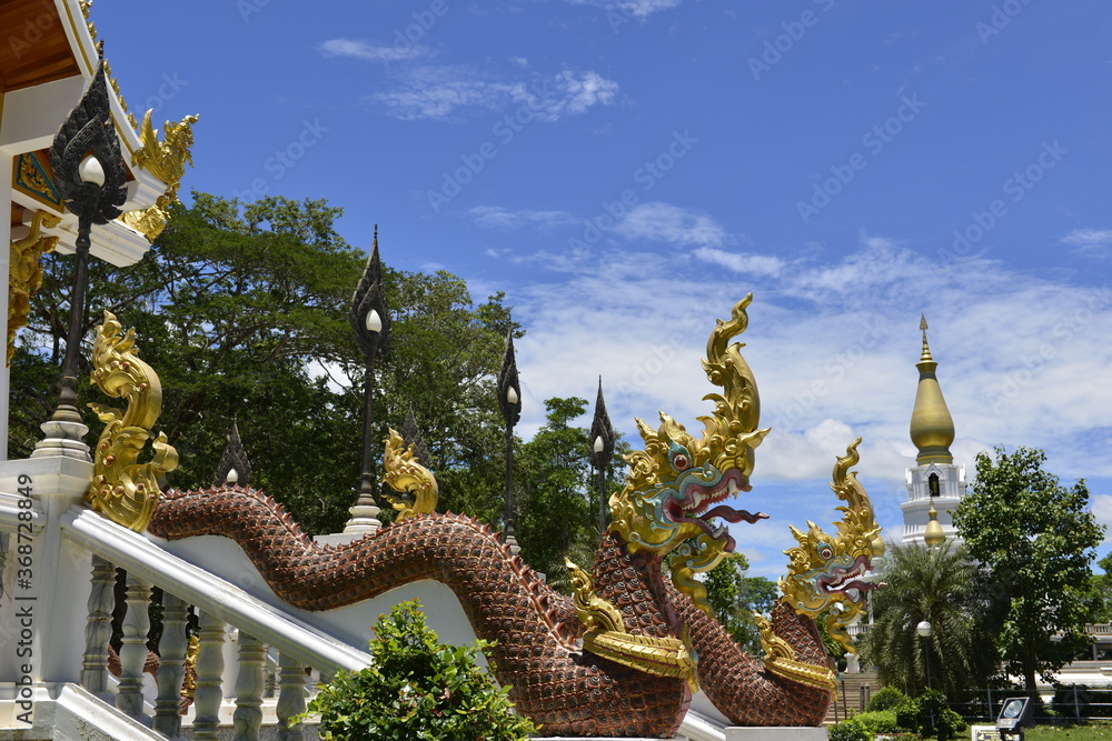 Fototapeta premium Naga Sculpture on staircase with Blue sky and pagoda background, Wat Aran Banphot Sri Chiang Mai District. Nong Khai Province, Thailand.