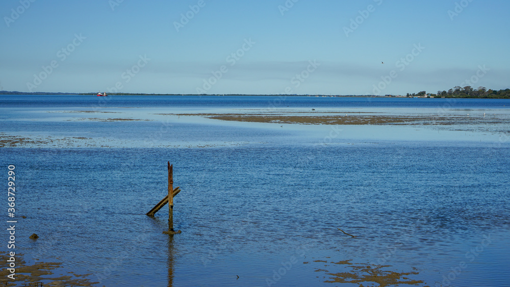 View across the blue water of Moreton Bay at low tide, with Redland Bay and islands in the distance. Victoria Point, Queensland, Australia.