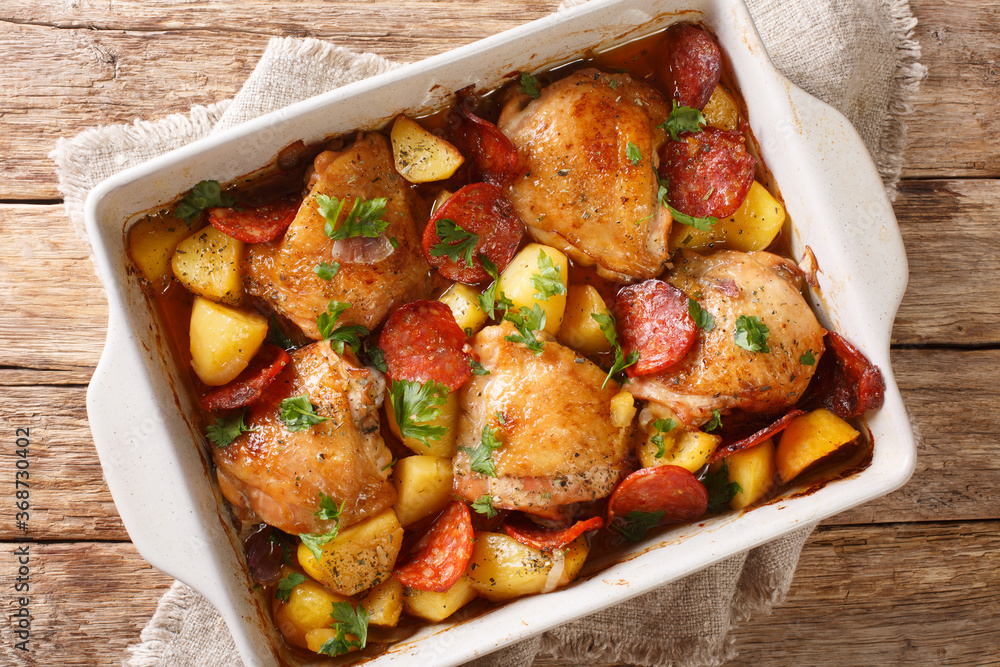 Traditional spanish food chicken with new potatoes and chorizo sausage close-up in a baking dish on the table. horizontal top view from above Traditional spanish food chicken with new potatoes and chorizo sausage close-up in a baking dish on the table. horizontal top view from above