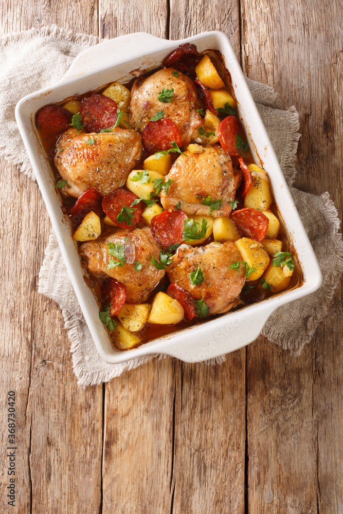 One pot of chicken with new potatoes and chorizo sausage close-up in a baking dish. vertical top view One pot of chicken with new potatoes and chorizo sausage close-up in a baking dish. vertical top view