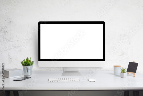 Computer display mockup on work desk. White work desk with plants, phone, box, keyboard and mouse. Web site design promotion template