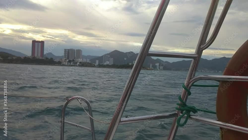 View of buildings and mountains from a moving ferry in the ocean. Boat sailing in the wavy ocean at morning, view of the city from afar. View of buildings and mountains from a moving ferry in the ocean. Boat sailing in the wavy ocean at morning, view of the city from afar.