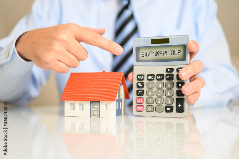 Berater in der Bank mit einem Einfamilienhaus und einem Taschenrechner auf dem Eigenkapital als Frage steht Berater in der Bank mit einem Einfamilienhaus und einem Taschenrechner auf dem Eigenkapital als Frage steht