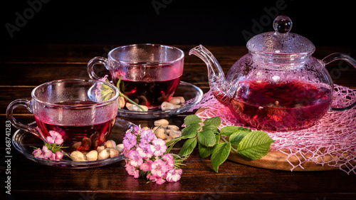 Tea parties  tea traditions and ceremonies. Zen traditions of the East.Green tea leaves or leaves of medicinal herbs lie on the table with a teapot and mugs of red tea  cashew nuts and clove flowers