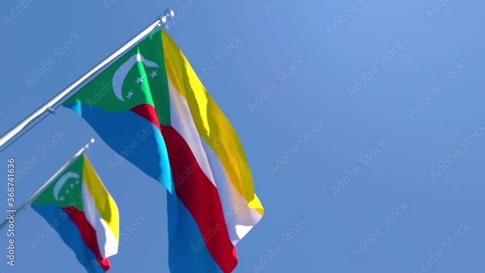 The national flag of Comoros is flying in the wind against a blue sky The national flag of Comoros is flying in the wind against a blue sky