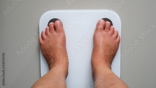 Diet concept. Female bare feet standing on scales
