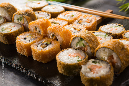 Set of fried sushi rolls with wasabi and ginger on black background. Japanese oriental cuisine