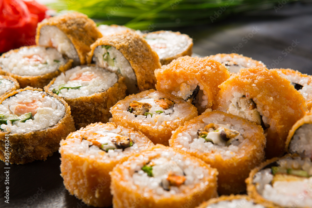 Set of fried sushi rolls with wasabi and ginger on black background. Japanese oriental cuisine Set of fried sushi rolls with wasabi and ginger on black background. Japanese oriental cuisine