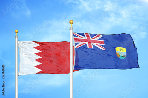 Bahrain and Saint Helena two flags on flagpoles and blue sky photo