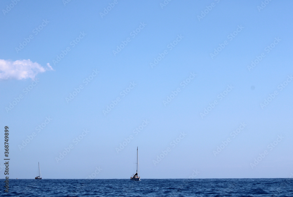 Mare con orizzonte cielo e due barche a vela