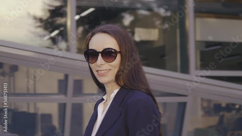 Caucasian attractive businesswoman walks in busines district corporate outdoor workspace. Busy people lifestyle. Technology.