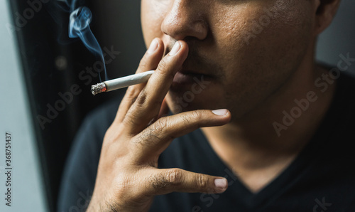 Close up young man smoking a cigarette darknest mood and tone. © Chanakon