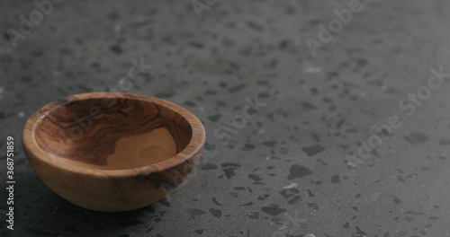 empty olive wood bowl on gray terrazzzo countertop