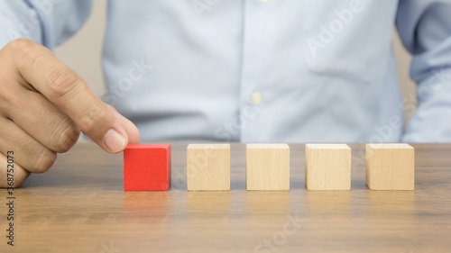Close-up hand choose a cube wooden toy blocks stacked without graphics for Business design concept and activity for child foundation practice skills.