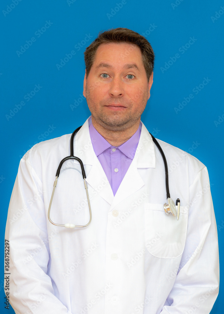 vertical photo A male doctor with a stethoscope smiling a clipboard while standing in a clinic. on light blue background vertical photo A male doctor with a stethoscope smiling a clipboard while standing in a clinic. on light blue background