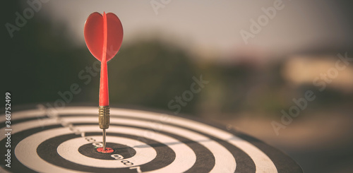 Bullseye or dart board has dart arrow throw hitting the center of a shooting target with sunshine for business targeting and winning goals business concepts.