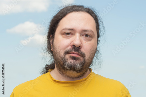 Bilde på lerret Adult man with a sloppy beard and disheveled hair with a slight smile against a