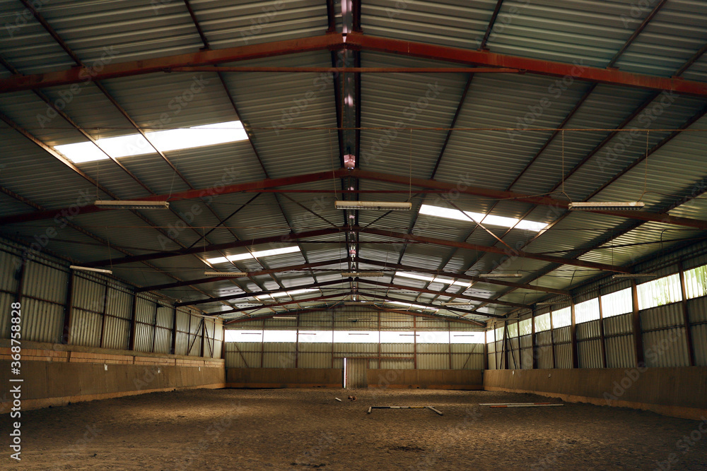 Empty riding hall with sandy covering without riders as an equestrian background Empty riding hall with sandy covering without riders as an equestrian background
