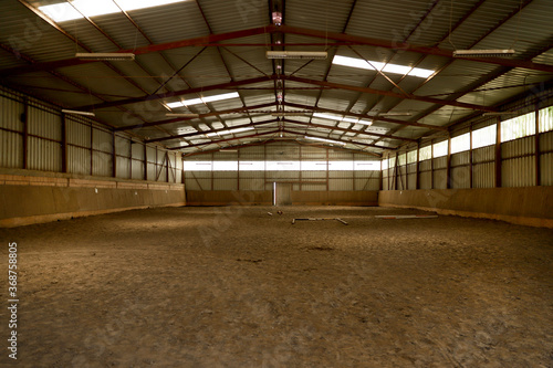 Empty riding hall with sandy covering without riders as an equestrian background
