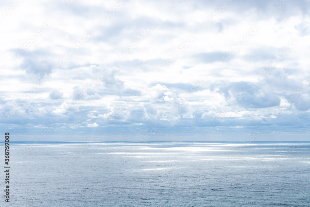calm blue sea and sun rays penetrating through the clouds in the sky. marine landscape