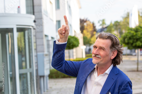businessman in his 50s standing outside pointing at something