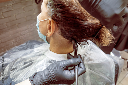 Hairdresser dyes woman hair. Hairdresser colorist dyes the hair of woman. Beautician, hand.