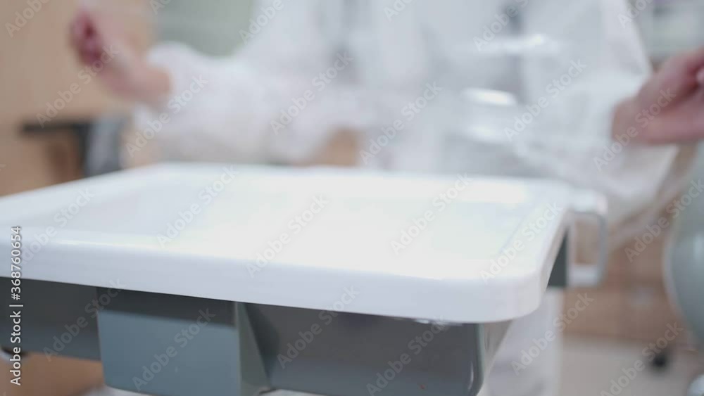 Medical nurse staff in white PPE suit wrapping dental equipment desk, disinfected preparation before dental operation, professional work, sterile clean hygiene items contaminated surface Medical nurse staff in white PPE suit wrapping dental equipment desk, disinfected preparation before dental operation, professional work, sterile clean hygiene items contaminated surface