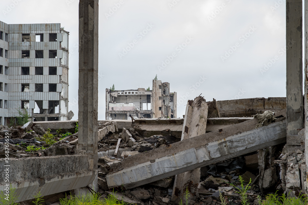 Fototapeta premium A large destroyed building with a pile of gray concrete debris and beams in the foreground. Background.