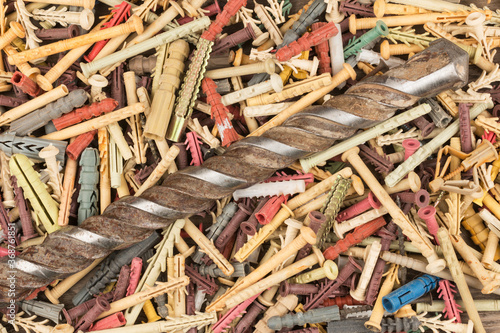 Old drill for drilling concrete lies on a pile of dowels. Close-up.