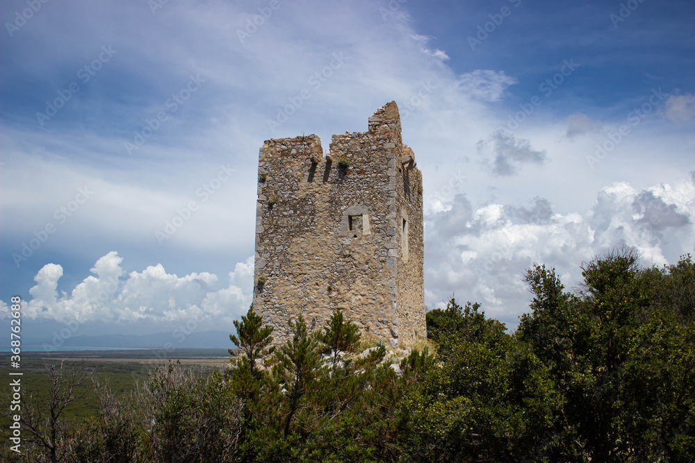Castel Marino tower against cloudy sky. Ruin of the ancient castle immense in the green. Maremma National Park, Tuscany, Italy. Castel Marino tower against cloudy sky. Ruin of the ancient castle immense in the green. Maremma National Park, Tuscany, Italy.