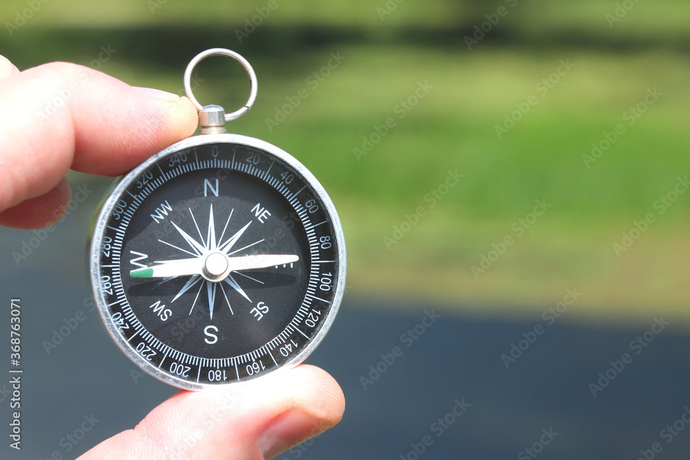 Old classic navigation compass in hand on natural background as symbol of tourism with compass, travel with compass and outdoor activities with compass Old classic navigation compass in hand on natural background as symbol of tourism with compass, travel with compass and outdoor activities with compass