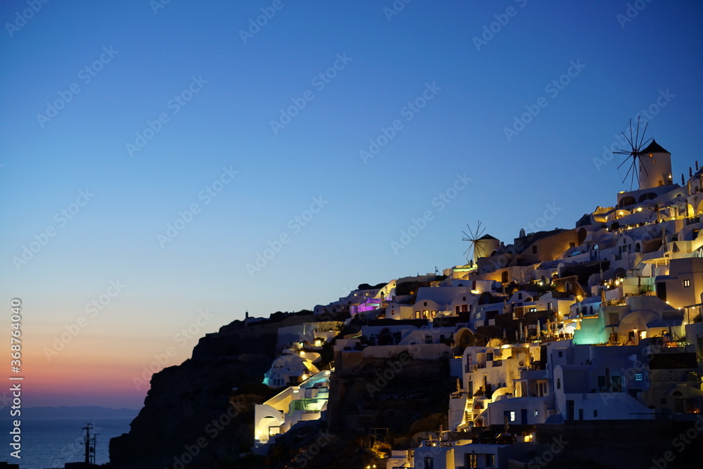 Fototapeta premium Sunset view and beautiful buildings lighted by sunset in santorini island, Greece, Europe