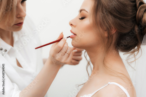 beautiful girl makeup artist makes make-up and paints her lips