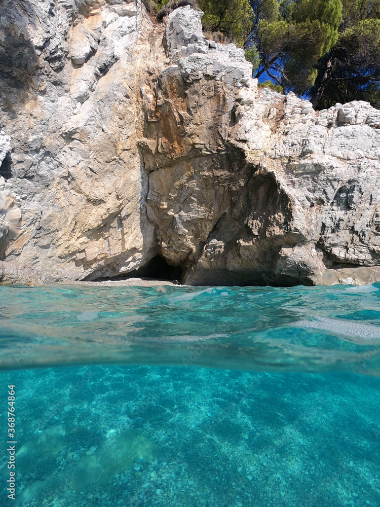 Underwater and sea level photo of amazing tropical rocky turquoise clear seascape with caves and natural pine trees Underwater and sea level photo of amazing tropical rocky turquoise clear seascape with caves and natural pine trees
