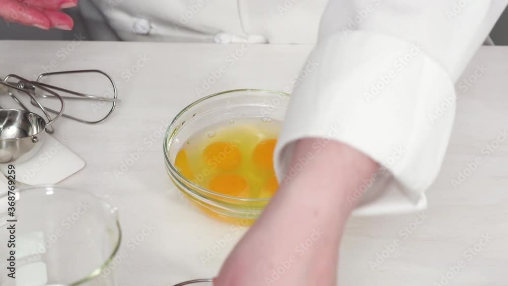 Step by step. Craking white organic eggs into a small glass bowl.