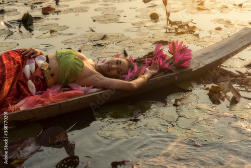 Young Asian women in Traditional dress in the boat and pink lotus flowers in the pond.Beautiful girls in traditional costume.Thai girl in retro Thai dress, Thai girl in traditional dress costume.